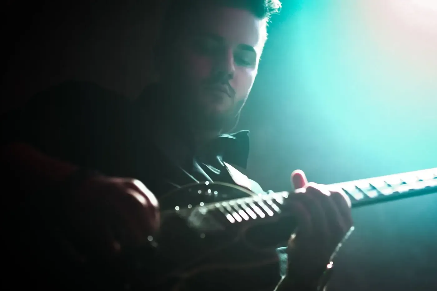 Maciej Mięso gra na gitarze w scenicznym świetle